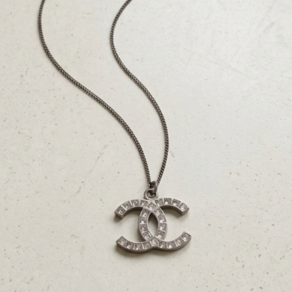 Silver Chanel CC rhinestone necklace styled flat lay