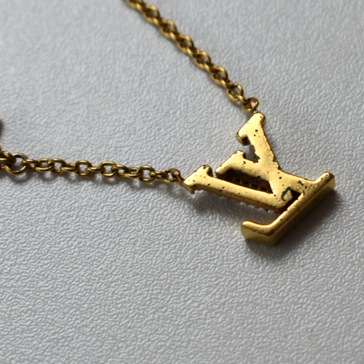 Back of gold Louis Vuitton rhinestone necklace pendant showing slight wear