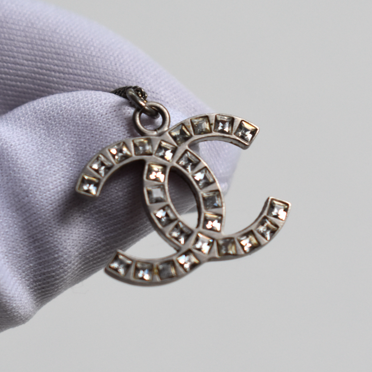 Close-up of silver Chanel CC pendant with rhinestone diamante detail